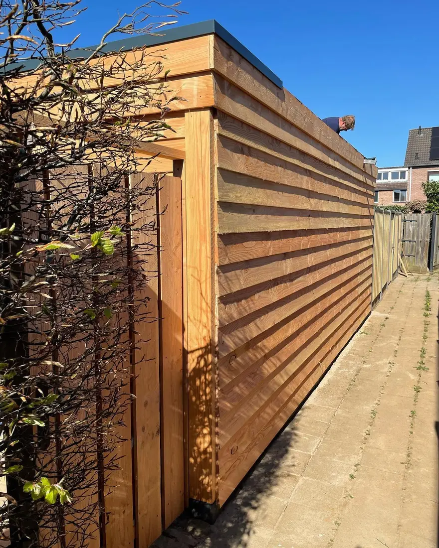 Tuinberging met een wand van liggende houten planken, in de zon